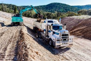 Excavator loading dirt into kenworth truck
