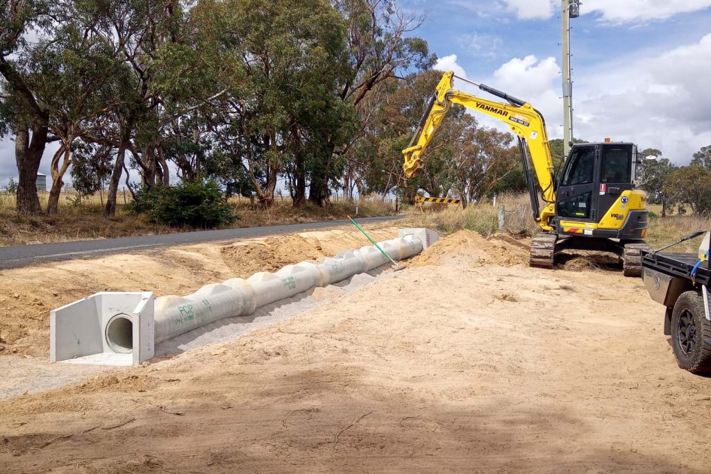 Laying pipe with excavator for site preparation
